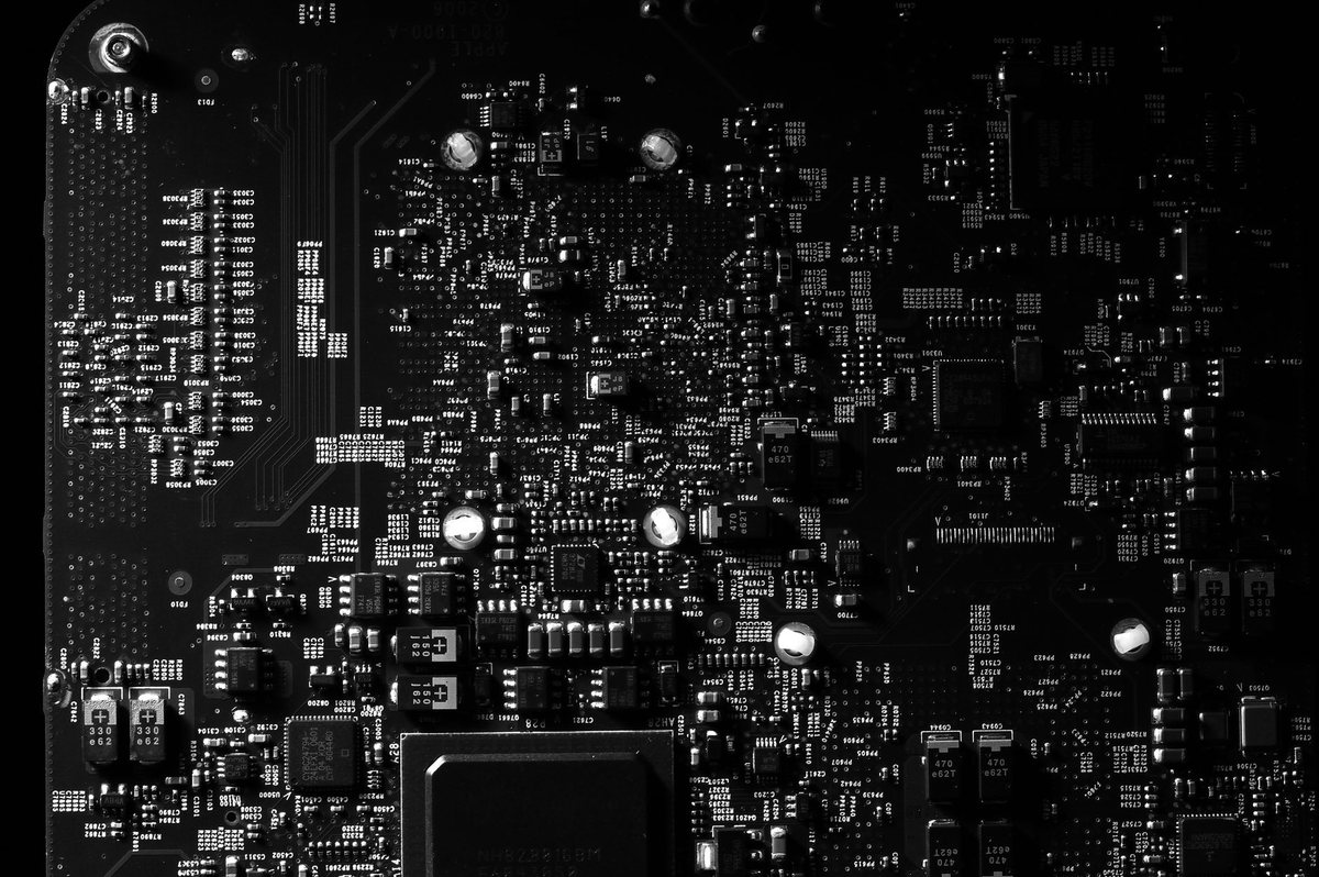 A high-resolution photo of a tiny surface-mounted microphone sensor on a green electronic circuit board.