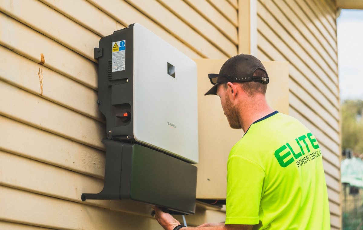 A wall-mounted electronic solar inverter unit installed inside a clean utility room.