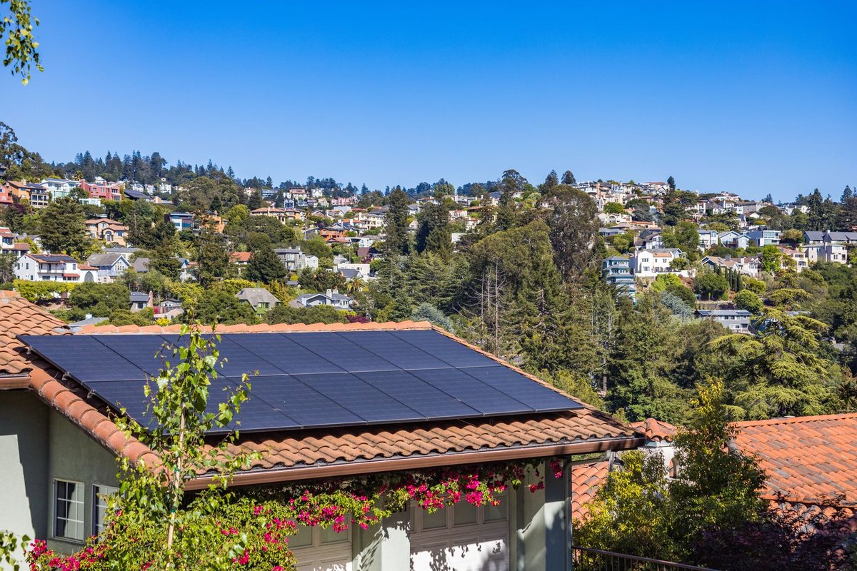 A neat residential rooftop solar array installed on a concrete terrace in an Indian city.