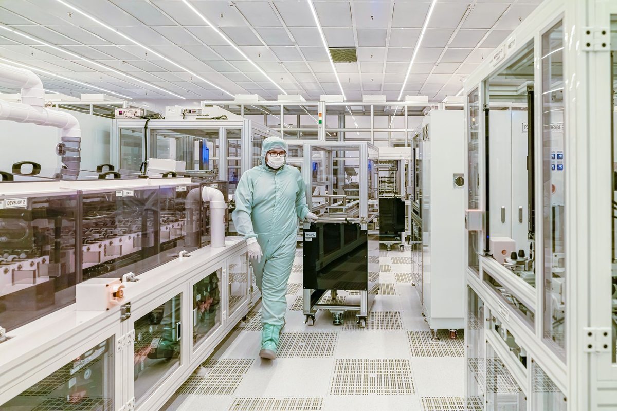 Wide view of a modern semiconductor fabrication cleanroom floor with automated equipment tracks.